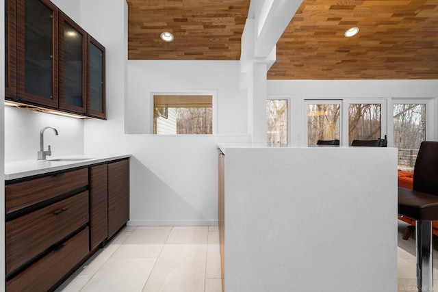 interior space with a healthy amount of sunlight, light tile patterned flooring, wood ceiling, and a sink