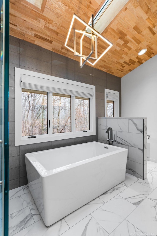 bathroom with wood ceiling, a freestanding tub, a notable chandelier, and marble finish floor