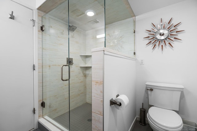 bathroom with a shower stall, toilet, and baseboards