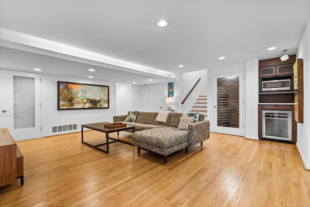 living room featuring light wood-type flooring, visible vents, a fireplace, and recessed lighting