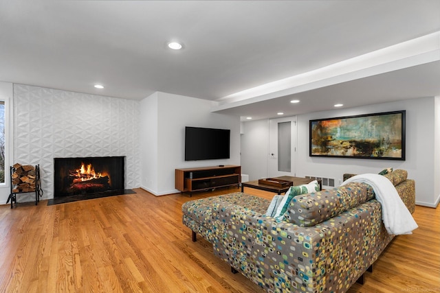 living area featuring visible vents, a tiled fireplace, wood finished floors, recessed lighting, and baseboards