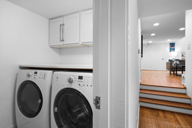 laundry area with cabinet space, recessed lighting, washing machine and dryer, and wood finished floors