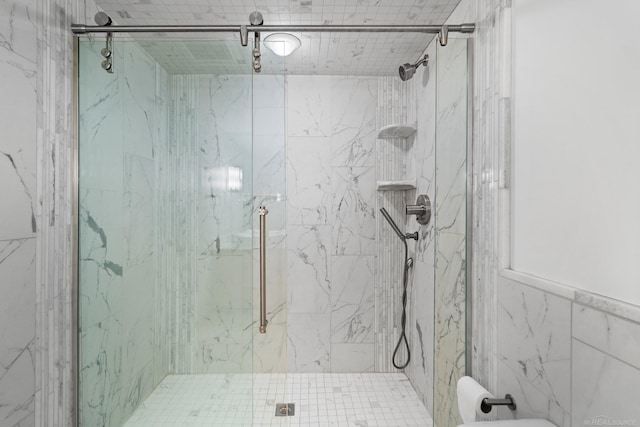 full bath featuring a marble finish shower and tile walls