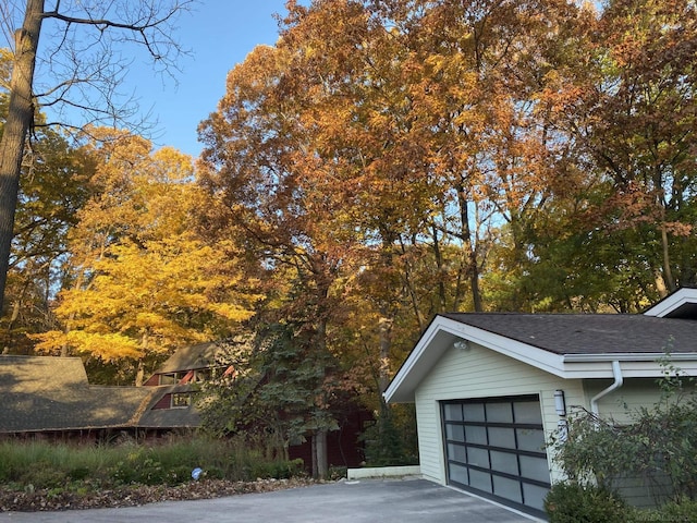 view of property exterior featuring a shingled roof and a garage