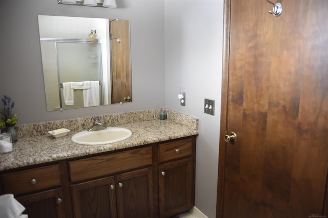 bathroom featuring a shower with door and vanity