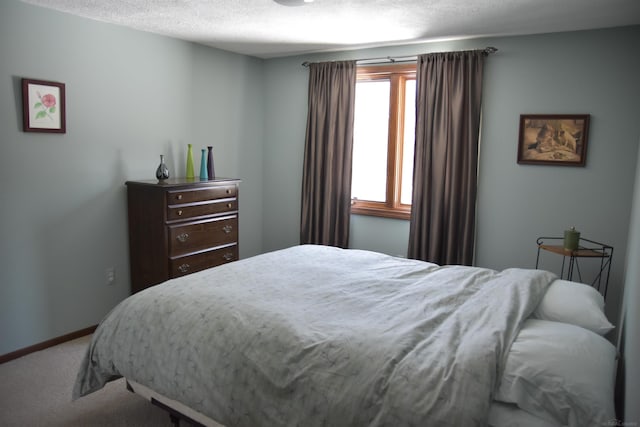 bedroom featuring carpet, baseboards, and a textured ceiling