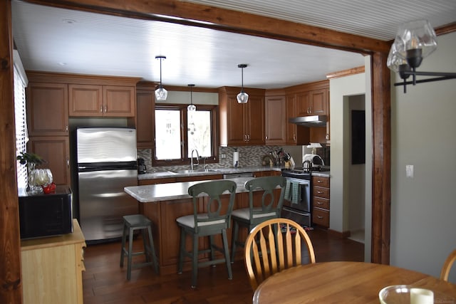 kitchen with a kitchen bar, a sink, tasteful backsplash, a kitchen island, and stainless steel appliances