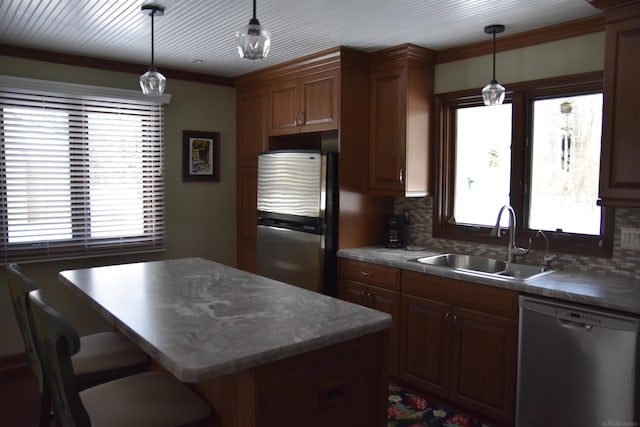 kitchen featuring pendant lighting, a sink, a kitchen island, appliances with stainless steel finishes, and decorative backsplash