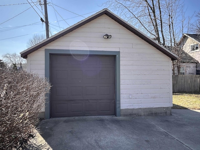 detached garage with concrete driveway and fence