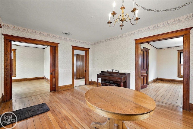 dining area with baseboards, light wood-style floors, a chandelier, and wallpapered walls