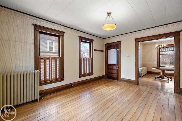 unfurnished room featuring wallpapered walls, radiator heating unit, baseboards, and light wood finished floors