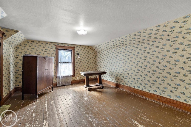 additional living space featuring hardwood / wood-style floors, a textured ceiling, baseboards, and wallpapered walls