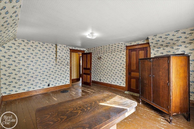 interior space featuring wallpapered walls, baseboards, and wood-type flooring