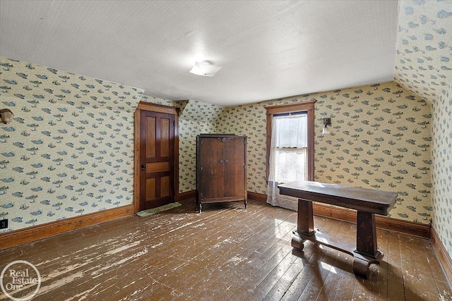 interior space featuring baseboards, hardwood / wood-style floors, and wallpapered walls