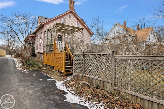 exterior space featuring a wooden deck, stairs, and fence