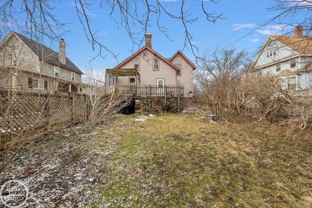 back of house with a wooden deck and a chimney