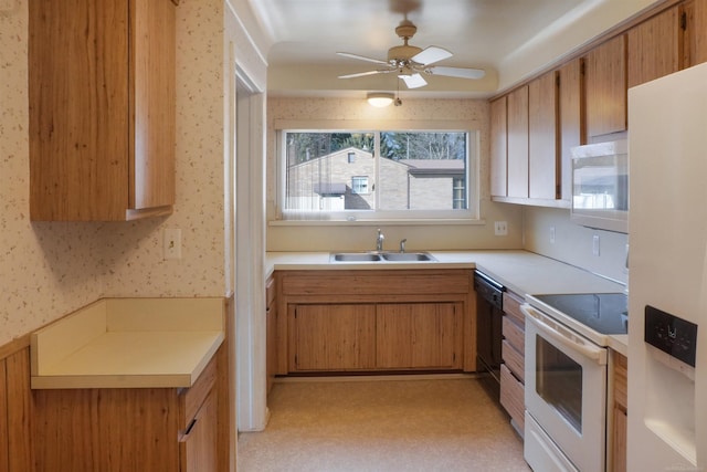 kitchen with wallpapered walls, white appliances, light countertops, and a sink