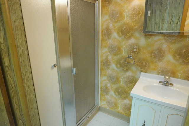 bathroom with vanity, baseboards, wallpapered walls, a stall shower, and tile patterned floors