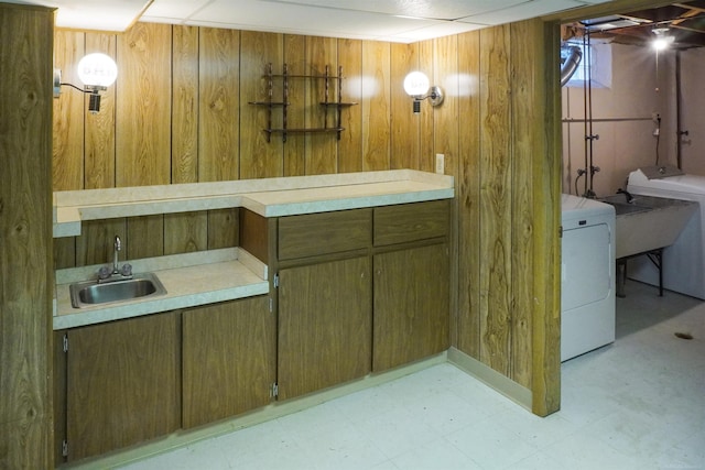 interior space with tile patterned floors, wooden walls, washer / dryer, and a sink