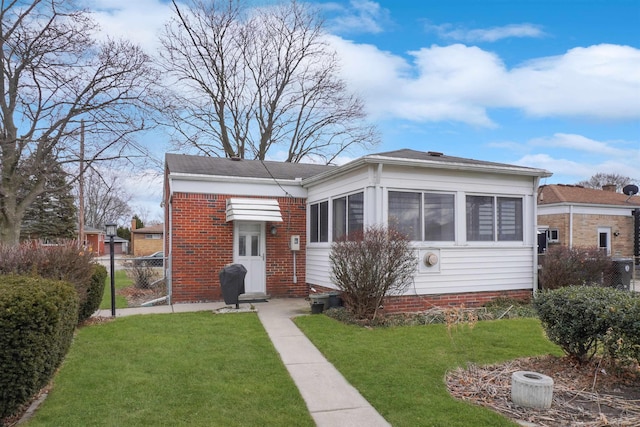 bungalow with brick siding, a front lawn, and fence