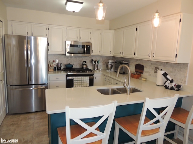 kitchen featuring a sink, a peninsula, backsplash, and stainless steel appliances