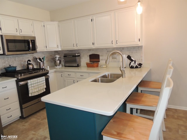 kitchen featuring a sink, white cabinetry, stainless steel appliances, a peninsula, and decorative backsplash