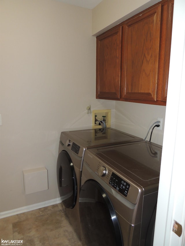 laundry area with cabinet space, separate washer and dryer, and baseboards