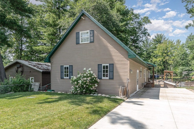 view of home's exterior with a yard, concrete driveway, and fence