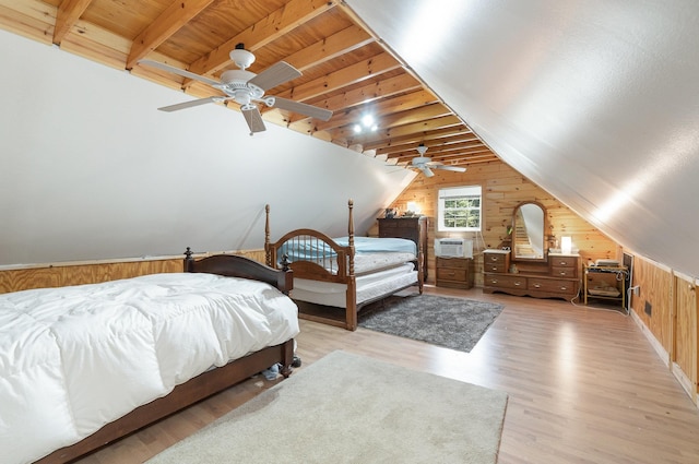 bedroom featuring a ceiling fan, lofted ceiling with beams, light wood-style floors, wooden walls, and wooden ceiling