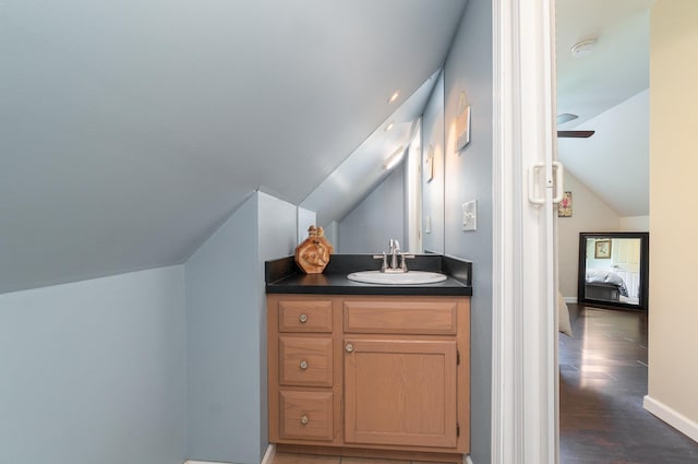 ensuite bathroom with ensuite bathroom, wood finished floors, baseboards, lofted ceiling, and vanity