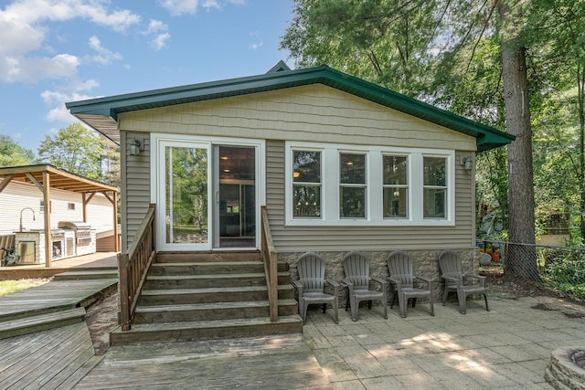 back of property featuring entry steps, a wooden deck, and fence