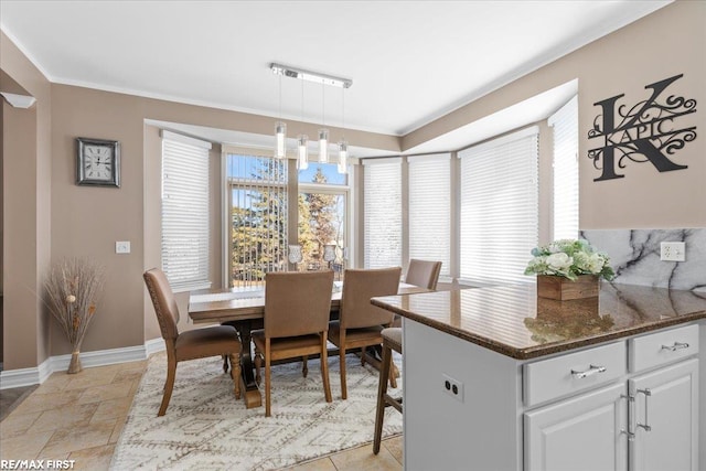 dining area featuring crown molding, baseboards, a wealth of natural light, and stone finish flooring