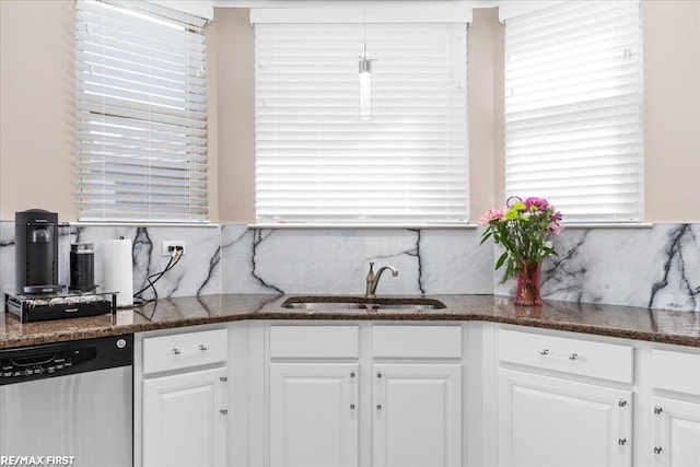 kitchen featuring dishwasher, dark stone counters, decorative backsplash, white cabinets, and a sink