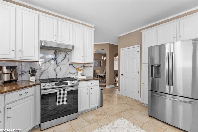 kitchen featuring backsplash, under cabinet range hood, appliances with stainless steel finishes, arched walkways, and white cabinets