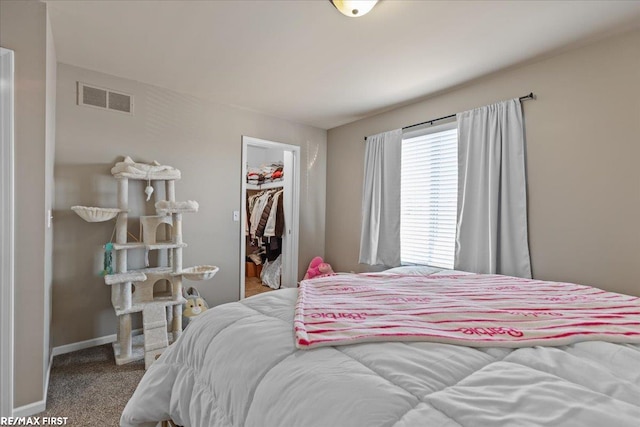 carpeted bedroom with a spacious closet, visible vents, baseboards, and a closet