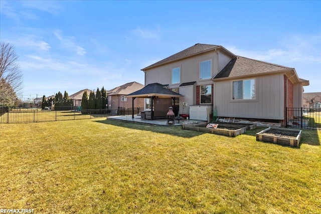 rear view of house featuring a gazebo, a fenced backyard, a lawn, and a vegetable garden