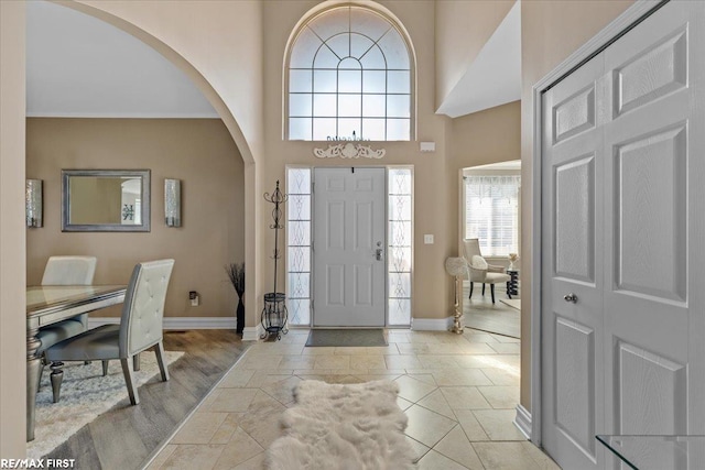 tiled entrance foyer with baseboards, a high ceiling, and arched walkways