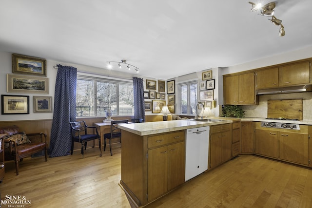 kitchen featuring stainless steel gas cooktop, a peninsula, a sink, light countertops, and dishwasher