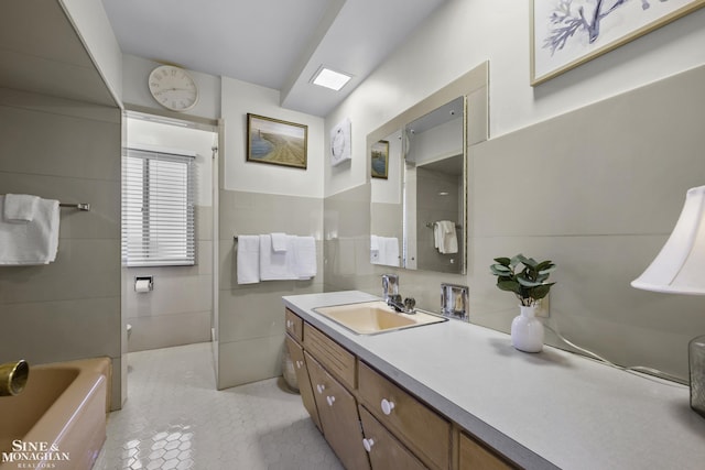 full bathroom featuring tile patterned flooring, a tub, tile walls, and vanity