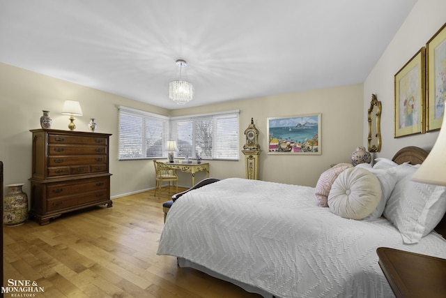 bedroom with light wood-style flooring, baseboards, and a chandelier