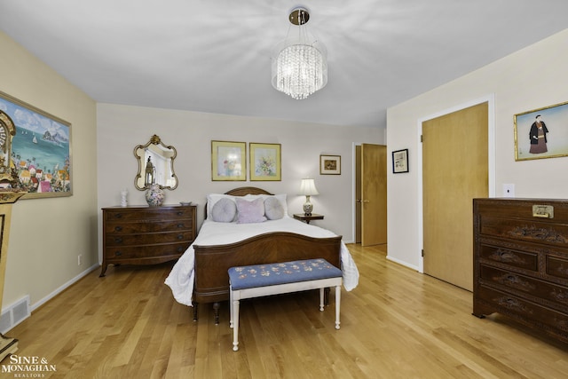 bedroom featuring visible vents, baseboards, light wood-style floors, and a notable chandelier