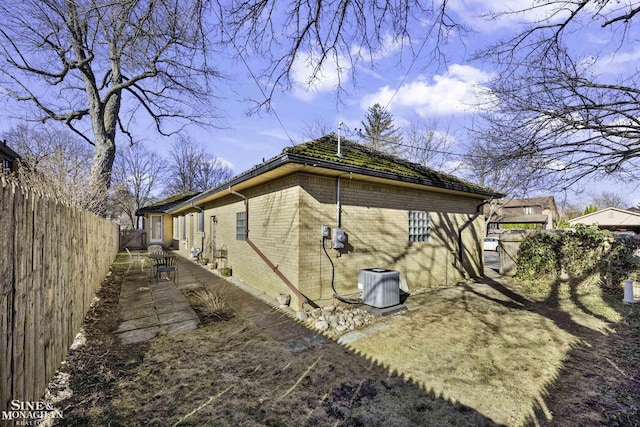 view of home's exterior featuring brick siding, central air condition unit, a patio, and a fenced backyard