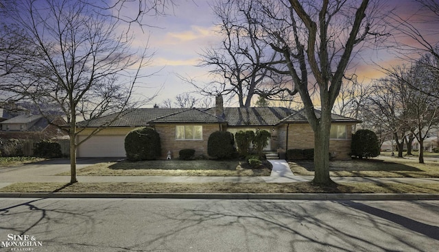 view of front of property featuring aphalt driveway, stone siding, an attached garage, and a chimney