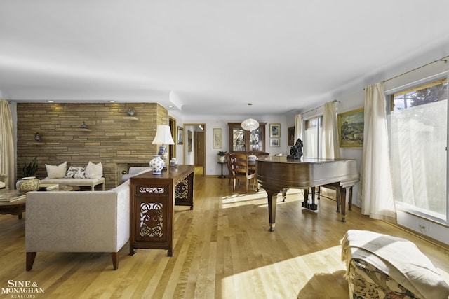 sitting room with a stone fireplace and light wood finished floors