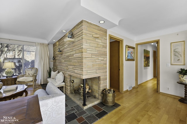 living room featuring wood finished floors, visible vents, baseboards, a fireplace, and recessed lighting