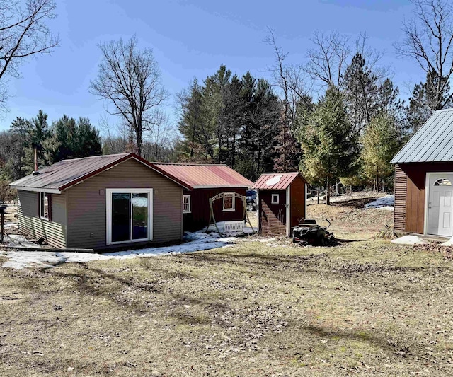 back of house featuring a storage shed, an outbuilding, and metal roof