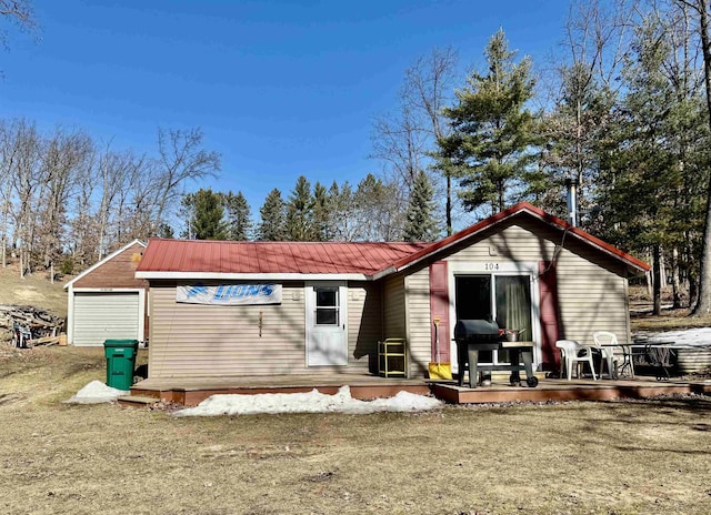 rear view of house with a deck, a garage, and metal roof