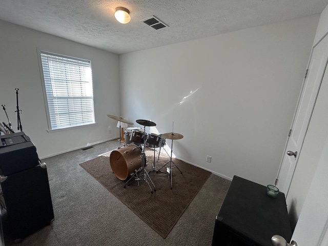 carpeted office space with visible vents, baseboards, a textured ceiling, and washer / dryer