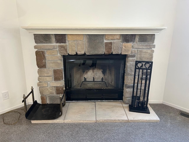 interior details with a glass covered fireplace, baseboards, visible vents, and carpet floors