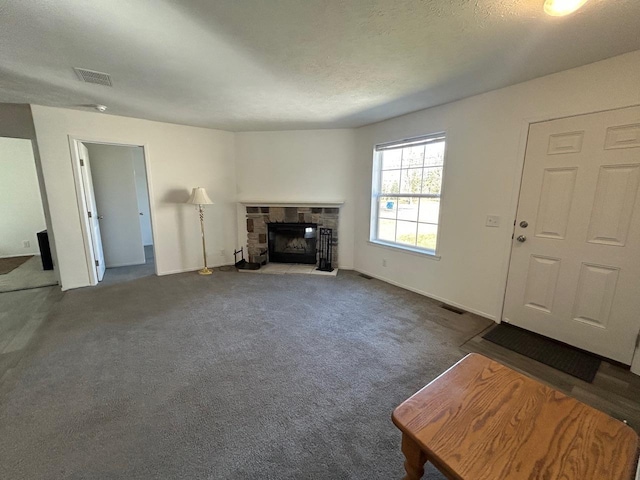 unfurnished living room featuring a stone fireplace, carpet flooring, visible vents, and a textured ceiling